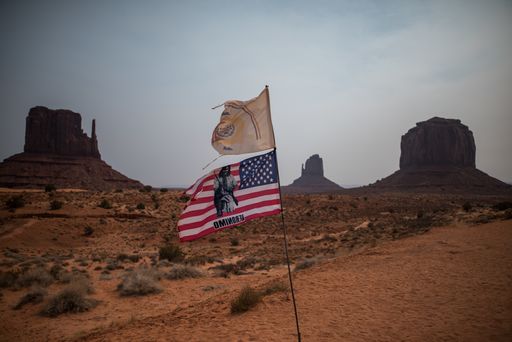 A horizontal shot of the flag of US with a Geronimo print in front of beautiful rock formations in Monument Valley, USA