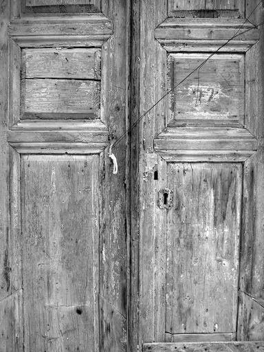 A grayscale shot of an old wooden door