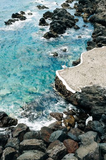A vertical shot of the sea surrounded by rocks under the sunlight - perfect for wallpapers