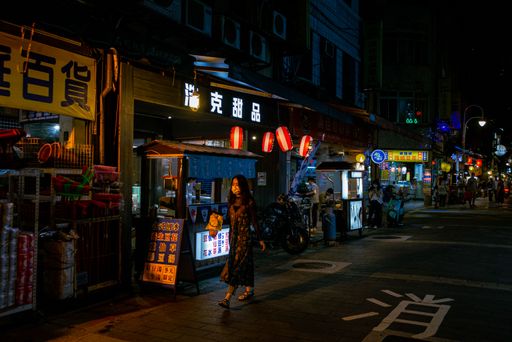 A view of a female walking in the street at night in Taipei, Taiwan