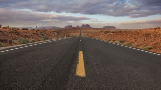 A horizontal shot of an empty road in the Monument Valley, USA with the background of the breathtaking sky