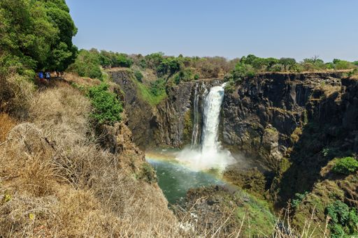 A beautiful shot of a waterfall surrounded by trees under a blue clear sky at daytime