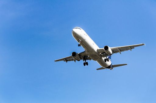 An aerial view of a commercial airplane soaring through a clear blue sky on a sunny day