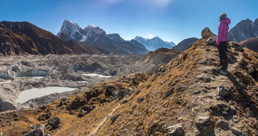 A landscape shot of a person in a pink jacket standing on a beautiful mountain valley during the day. Perfect for a hiking scenario.