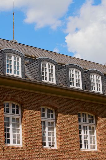 A vertical shot of an old style building exterior with red bricks and tiled roof in the daylight