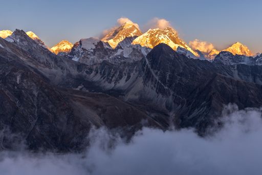 A breathtaking shot of beautiful white mountain peaks covered in clouds. Perfect for a wallpaper or a background.