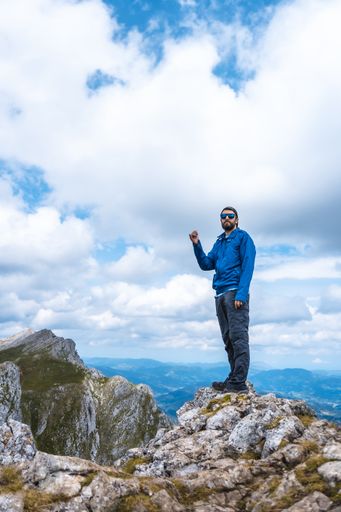 A vertical shot of a man standing on the top of the mountain Aitzkorri in Gipuzkoa - the concept of victory