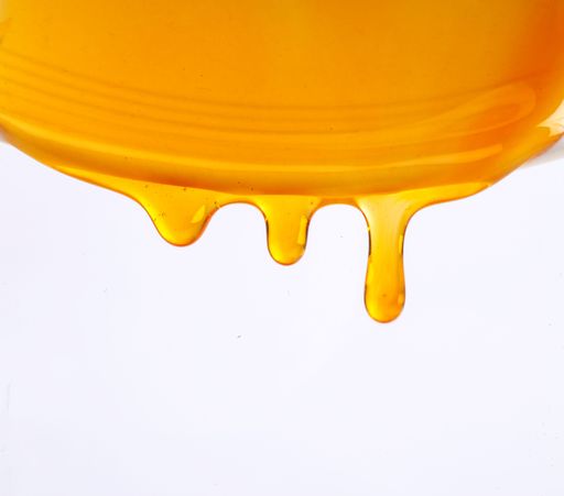 A closeup of honey dripping on a white background