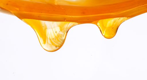 A closeup of honey dripping on a white background