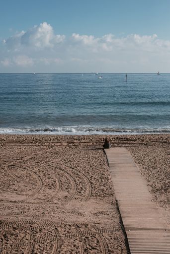 A vertical shot of a lonely woman sitting on the shore of the sea in Barcelona, Spain
