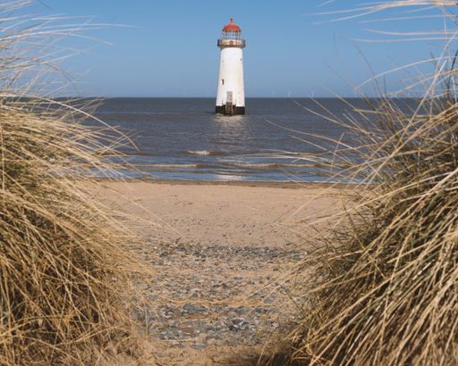 The Point of Ayr Lighthouse in Wales visible from the dry grass area