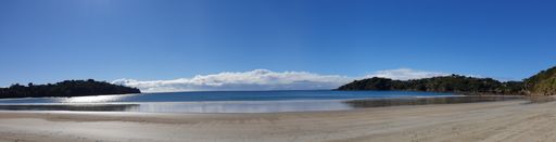 A wide angle shot of the water on the beach under the blue sky