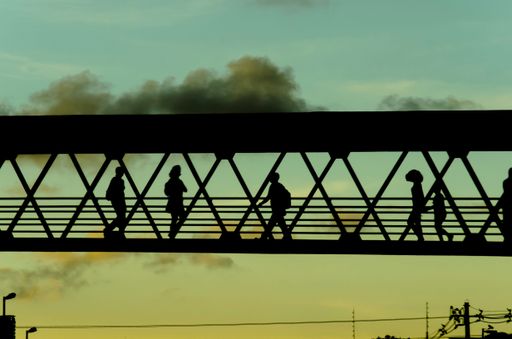 A silhouette of pedestrians walking on a bridge under a sunset sky in Salvador city, Bahia, Brazil