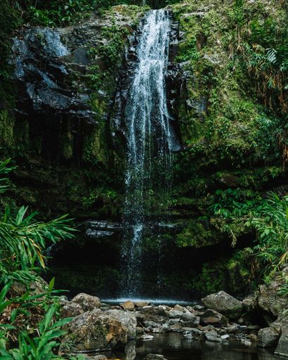 A vertical shot of a thin waterfall flowing down from a cliff.