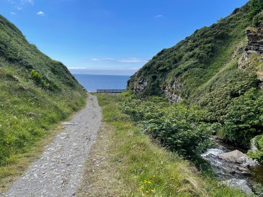 A beautiful shot of a dirt road in the middle of mountains directed to the sea.