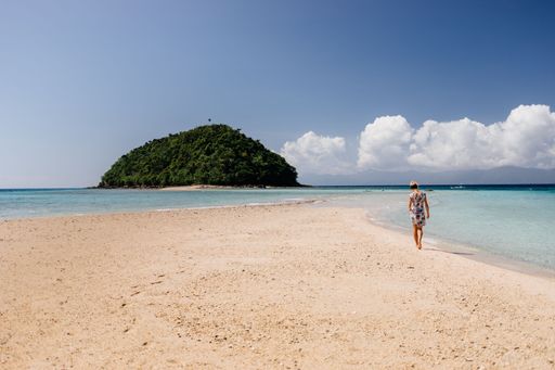 A mesmerizing view of the sandy Bon Bon Beach and a cliff with dense trees in the distance in Romblon, Philippines