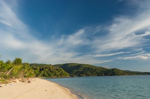 A mesmerizing view of the sandy Bon Bon Beach and a mountain with dense trees in Romblon, Philippines