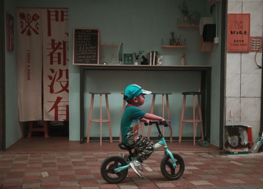 A kid riding a blue bicycle on a street in Macau, China