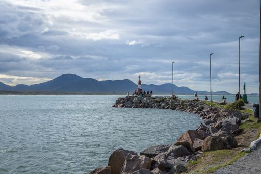 The cloudy sky over the sea with pier leading to a lighthouse
