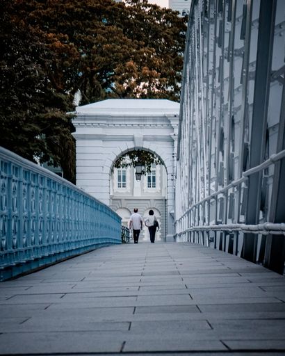 A rear view of a couple walking on a bridge