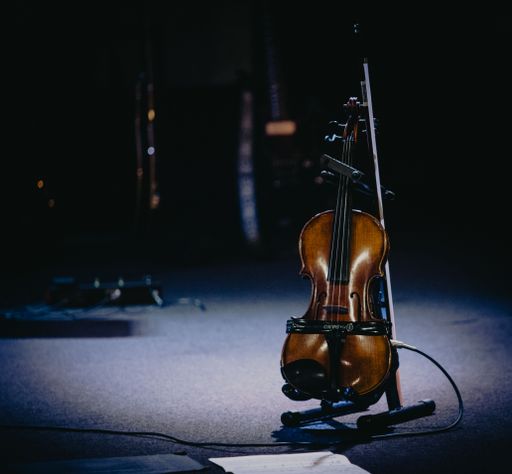 A vertical shot of a cello on the stage with a dark background