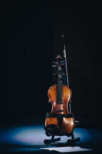 A vertical shot of a cello on the stage with a dark background