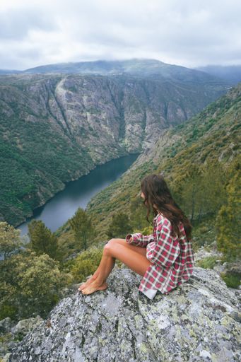 A vertical shot of a young Caucasian woman in Sil Canyon in Spain