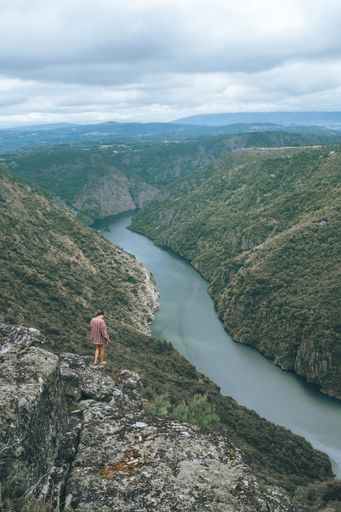 A vertical shot of a young Caucasian woman in Sil Canyon in Spain
