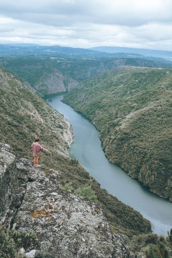A vertical shot of a young Caucasian woman in Sil Canyon in Spain