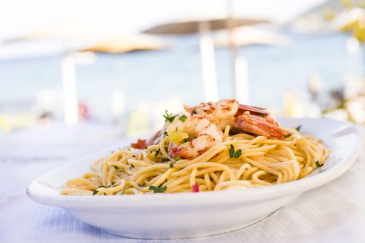 A selective focus shot of tasty pasta with shrimps in a white plate