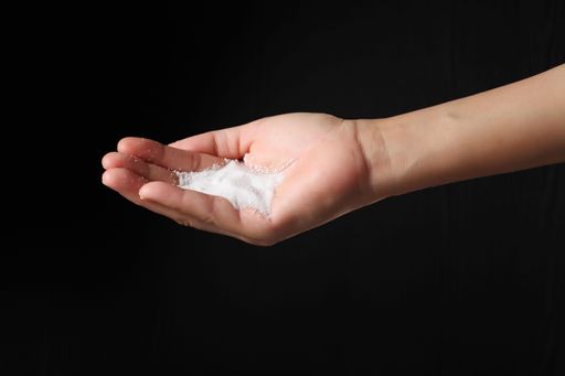 A male hand holding sea salt isolated on a black background