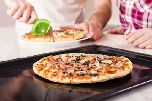 A shallow focus closeup shot of people cutting delicious homemade pizza