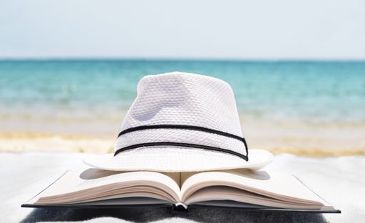 A shallow focus shot of a white hat on an open book in the beach