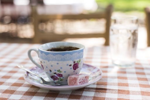 A selective focus shot of a cup of coffee with a sweet on an outdoor table