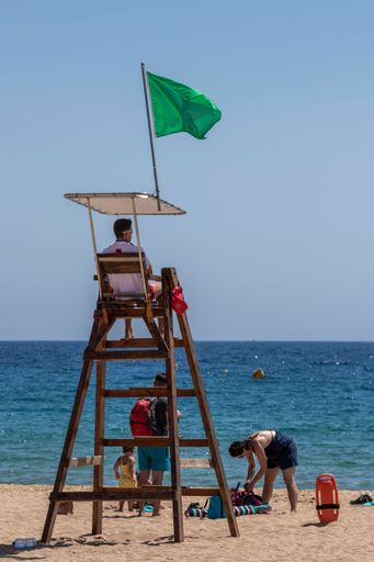A vertical shot of a lifeguard sitting in a watchtower on Palamos beach in Costa Brava, Spain in summer