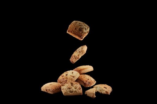 Freshly baked chocolate chips cookies falling on the black surface isolated on black background