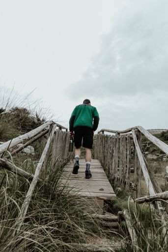 A vertical shot of a person walking up the stairs under the cloudy sky