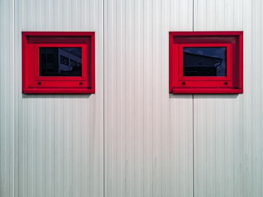 A horizontal shot of a white wall with small red rectangular windows. Perfect for a background.