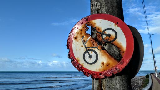 A closeup shot of a rusted bicycle sign on a seafront promenade