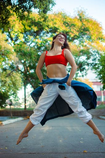 A vertical shot of a Hispanic female dancing barefoot outdoors