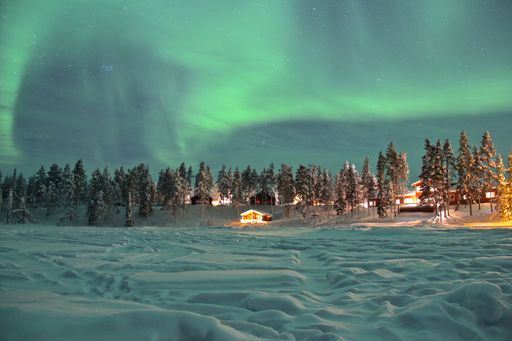 A beautiful snowy landscape with trees and Northern Lights in the sky in Lapland, Finland