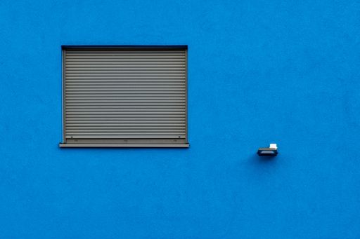 A horizontal shot of a blue wall with a grey window blind - great for a cool wallpaper or background