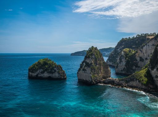 A scenic aerial view of high rocks at a white sand beach of Nusa Penida, Bali, Indonesia