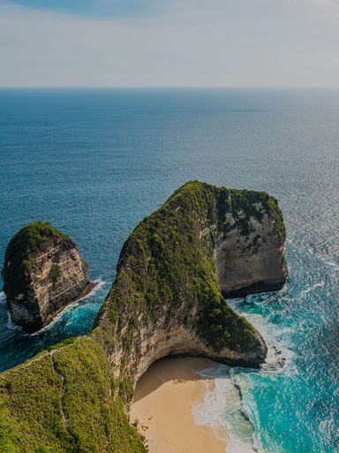 A scenic aerial view of high rocks at a white sand beach of Nusa Penida, Bali, Indonesia