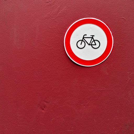 A closeup shot of a red wall with a round bicycle sign. Perfect for a bicycle piece.
