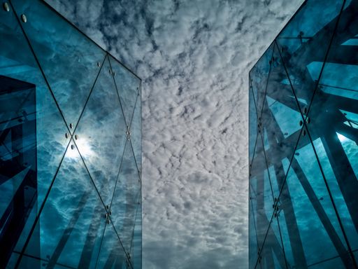 A horizontal low angle shot of the breathtaking cloudy sky between two buildings with glass walls