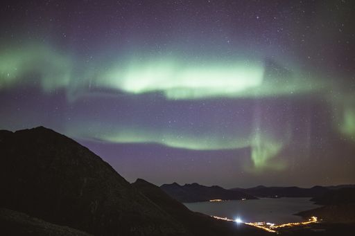 The beautiful mountains near the lake with the background of a breathtaking view of aurora at night