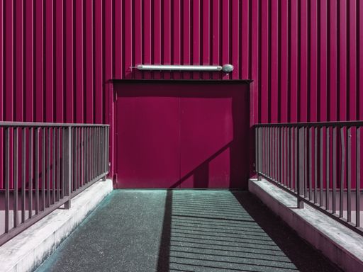 A horizontal shot of a purple building with metal walls and grey railings during daytime