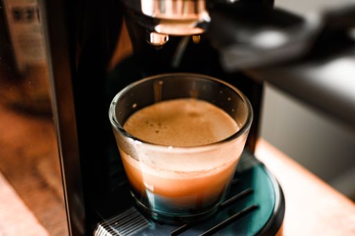 An espresso coffee coming out from an automated coffee maker machine