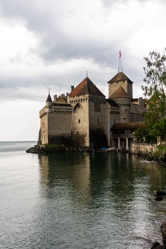 A vertical beautiful shot of an ancient Chillon Castle next to a lake Geneva in Switzerland,